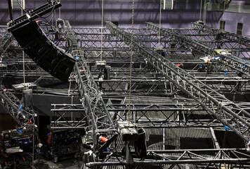 Black steel trusses and line array speakers are lifted by chain hoists. Installation of...
