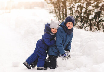 Fototapeta na wymiar Children play in the winter outdoors with snow. Happy brother and sister together