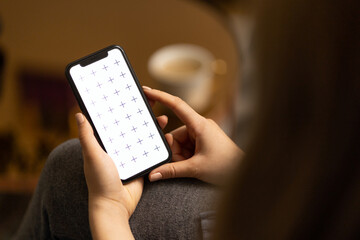 Obraz premium Young women holding her phone in in hand, reading news, browsing internet or digital application, watching video, with white coffee on the table