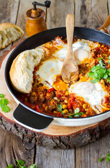 Fried vegetable with egg (shakshouka) on wooden table