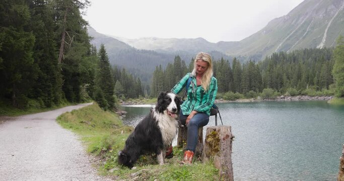 Mature adult woman by lake enjoying scenic nature landscape , with border collie dog pet outdoors