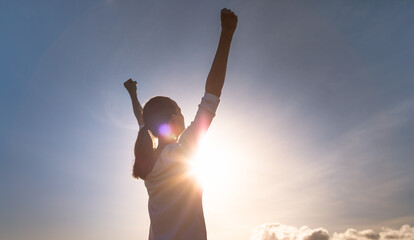 Feeling inspired. Young woman with fist up to sky feeling strong and motivated. 