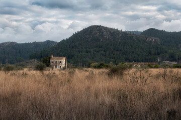 Old country house, with mountains in the background and a cloudy sky at dusk in the winter.