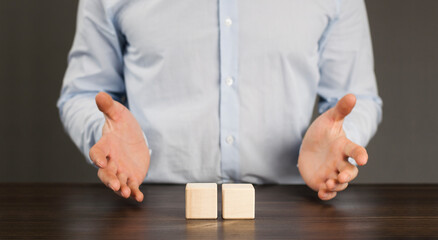 Wooden blocks cubes on the table. Man holding businessman in his hands. Growth and construction concept.