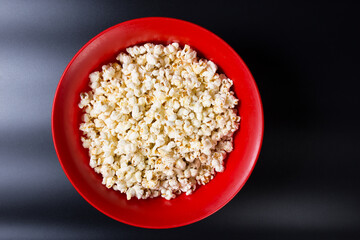 Popcorn in a red bowl. Popcorn on black background.