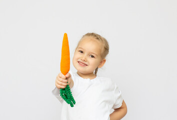 Happy little girl holding a knitt carrots. Concept of healthy food.