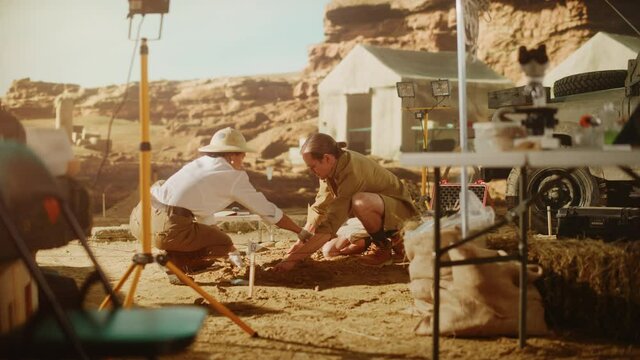 Archeological Digging Site: Two Great Archeologists Work on Excavation Site, Carefully Cleaning, Lifting Newly Discovered Ancient Civilization Cultural Artifact, Historic Clay Tablet, Fossil Remains