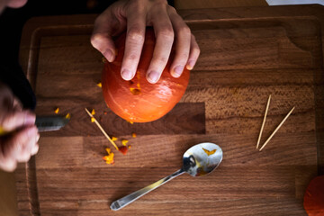 A woman carves a Halloween pumpkin