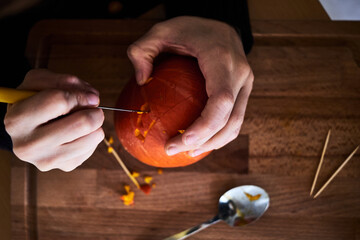 A woman carves a Halloween pumpkin