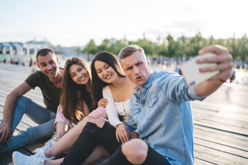 Obraz premium Multiethnic friends having fun and taking selfie in park