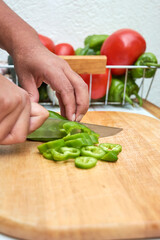 woman cutting peppers Gazpacho, Andalusian and some ingredient to prepare it, such as tomato, garlic and onion, cucumber on a white rustic table, served in traditional Andalusian glazed ceramic plates