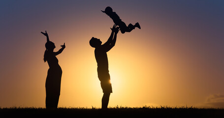 Fototapeta na wymiar Mother and father playing with child lifting him up in the air. 