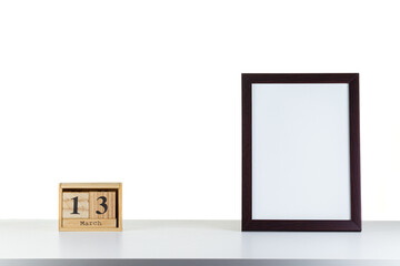 Wooden calendar 13 march with frame for photo on white table and background