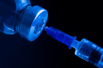 Medical vial with medicine and syringe for injection on a blue background.