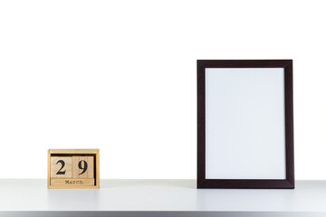 Wooden calendar 29 march with frame for photo on white table and background