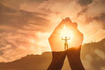 The power of prayer. Worshiping hands up to the sunrise and strong woman motivated standing on a...
