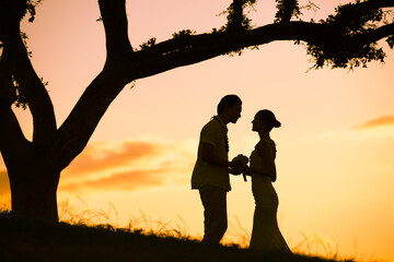 Silhouette of just married couple feeling involve  at sunset