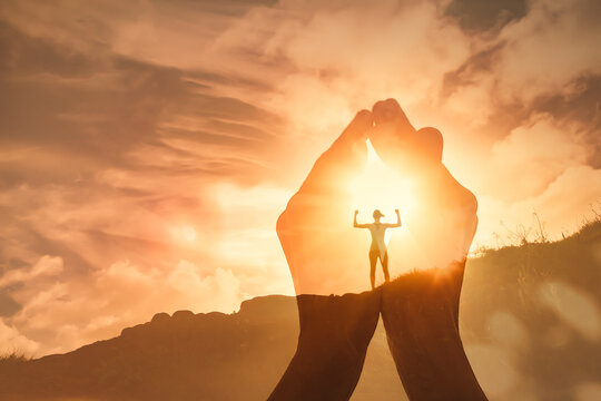 The power of prayer. Worshiping hands up to the sunrise and strong woman motivated standing on a mountain top. 