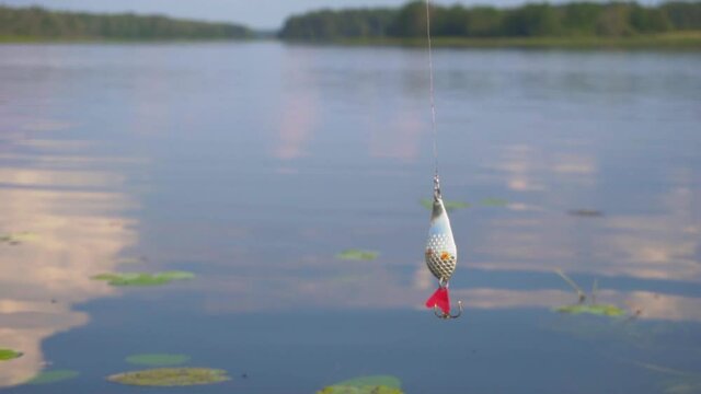 Fishing lure hanging over the lake. Vobler for fishing.
