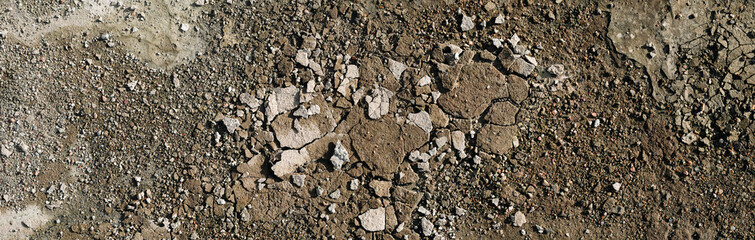 Rough grunge floor surface with small crumbled remains of concrete plaster and small stones. High resolution surface texture illuminated by sunlight. Panoramic banner