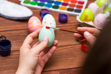 A woman with a tassel paints Easter eggs. Preparing decorations for Easter, creativity with...