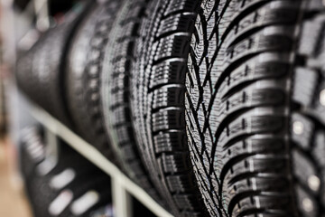 Fototapeta close-up new tires in the auto repair service center, brand new winter tires with a modern tread isolated. selective focus. tire stack background.winter season, no people obraz