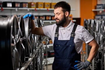 adult auto mechanic man in uniform have rest after hard working day, standing by rack of car...
