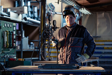 Fototapeta na wymiar Portrait of a smiling welder posing in the factory