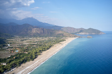Obraz premium Aerial view of sea coast with mountains in the background. Top view of the seaside of resort town. Summer vacation conept.