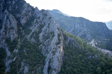 Close up of a mountain range with green trees over the road. View of scenic rocky cliff on summer day. Nature background.
