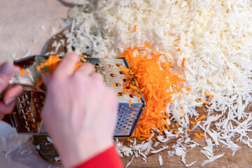 Woman rubbing carrots. Sauerkraut with carrots. Pickled cabbage. Sauerkraut cooking process.
