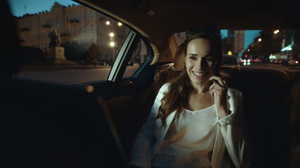 Fototapeta na wymiar Playful female professional talking mobile phone in car. Working woman overtime