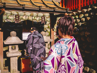 Girls with kimono taking photos in front of stone lamps of stone lamp at Fushimi Inari taisha shrine, Kyoto, Japan