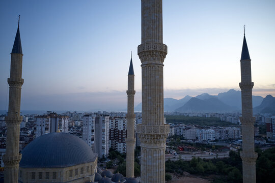 Mosque of the four minarets. High-rise buildings of a modern city with mountains in the background. Picturesque urban landscape in the evening. Antalya, Turkey.