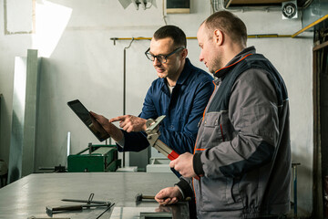 A tinsmith and his fellow colleague engineer in the workshop - obrazy, fototapety, plakaty