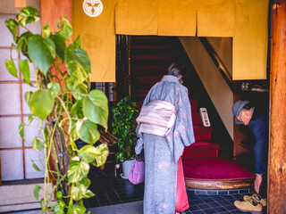 Old couple (woman with kimono) taking off their shoes when entering a traditional house (restaurant or tea house) at Kyoto, Japan