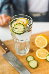 Homemade lemonade with cucumber and lemon is on a white table in the kitchen. Detox and diet food