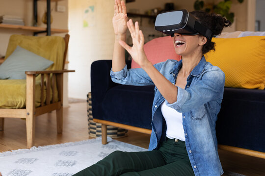 Caucasian woman smiling wearing vr headset sitting on floor at home