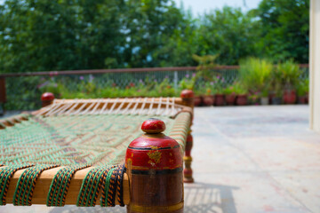Bokeh style photo of charpai desi Indian Pakistani traditional bed made of woven rope mesh with beautiful red legs.