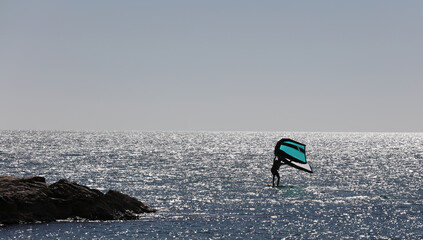 Man practicing with wing-surfer at sunset in the sea