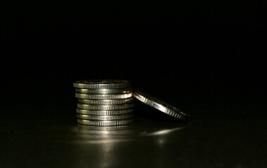 silver coin stack isolated on a black background. Space for text