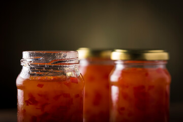 Pepper jelly in glass jar on the table. Image with selective focus.