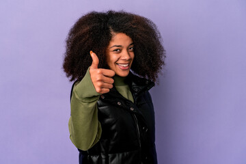 Young african american curly woman isolated on purple background smiling and raising thumb up