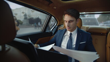 Focused male professional searching right info in documents in automobile.