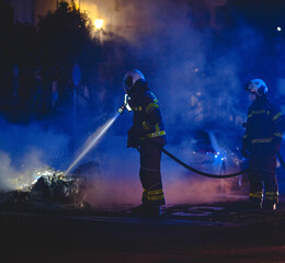 Bomberos apagando incendio de contenedor en llamas por la noche en Granada (España)