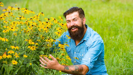 Naklejka na ściany i meble Smiling man with flowers. Spring mood. Sunny portrait. Carefree and positive thinking. Rudbeckia flower.