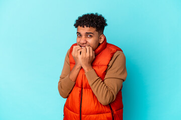 Young african american curly man isolated on blue biting fingernails, nervous and very anxious.