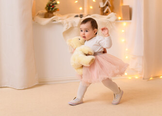 portrait of a baby girl in home interior decorated with lights and holiday gifts