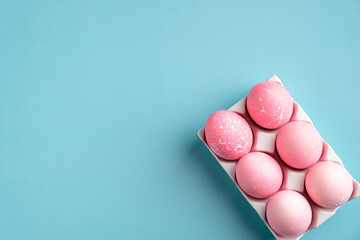 Happy Easter minimal concept. Creative layout with pink Easter eggs in holder on turquoise background. Flat lay, top view, copy space.