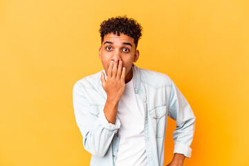 Young african american curly man isolated on purple shocked, covering mouth with hands, anxious to discover something new.